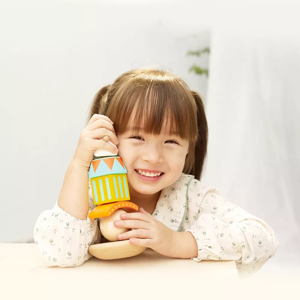 Balansuojantis klaunas ant medinių kaladėlių piramidės